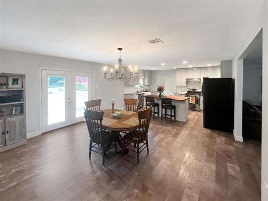 dining area featuring an inviting chandelier, dark hardwood / wood-style floors, and french doors