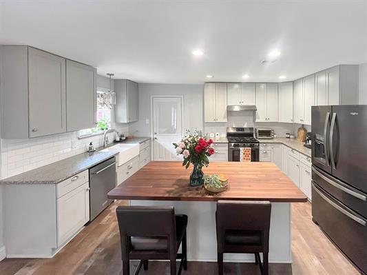 kitchen featuring appliances with stainless steel finishes, gray cabinetry, light hardwood / wood-style floors, decorative backsplash, and butcher block counters