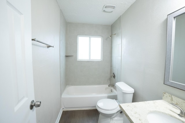 full bathroom featuring hardwood / wood-style flooring, tiled shower / bath combo, vanity, a textured ceiling, and toilet