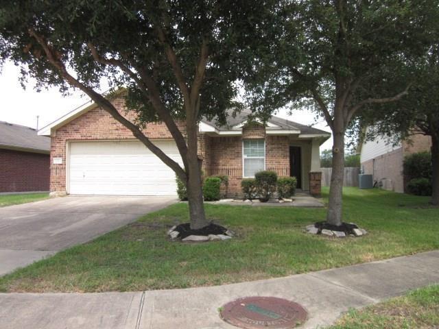 ranch-style home featuring a garage, cooling unit, and a front lawn