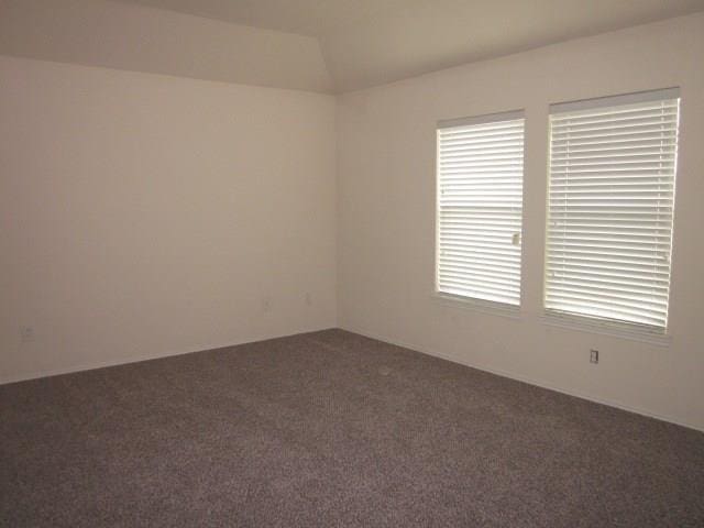 unfurnished room featuring dark colored carpet and vaulted ceiling