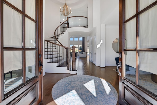 entryway featuring a towering ceiling, dark wood-type flooring, and a chandelier