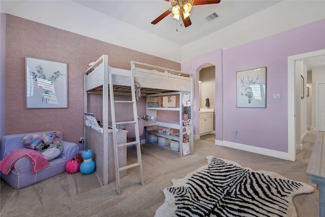 bedroom featuring ensuite bathroom, light carpet, and ceiling fan