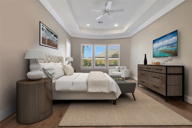 bedroom featuring multiple windows, hardwood / wood-style floors, a raised ceiling, and ceiling fan