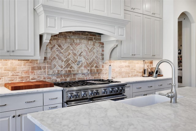 kitchen featuring white cabinetry, double oven range, sink, and backsplash