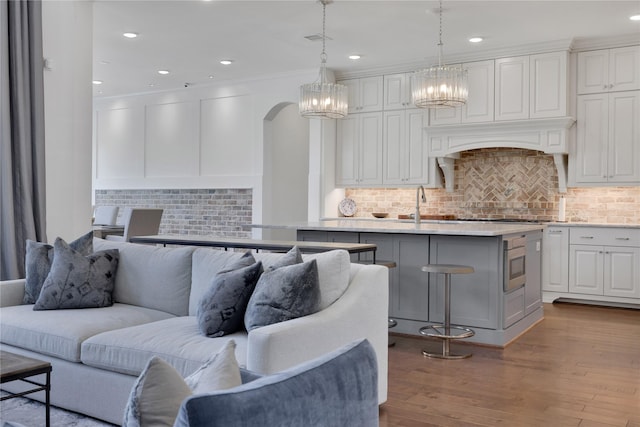 living room featuring sink, crown molding, and light hardwood / wood-style floors