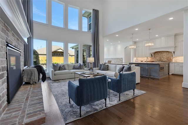 living room featuring a towering ceiling, dark wood-type flooring, and a notable chandelier