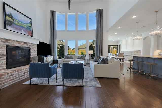 living room featuring dark wood-type flooring, a towering ceiling, and a fireplace