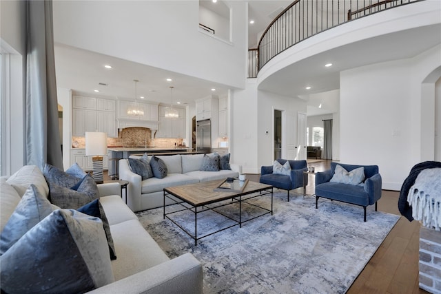 living room featuring an inviting chandelier, a towering ceiling, and light hardwood / wood-style flooring