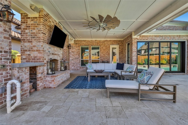 view of patio / terrace featuring ceiling fan and an outdoor living space with a fireplace