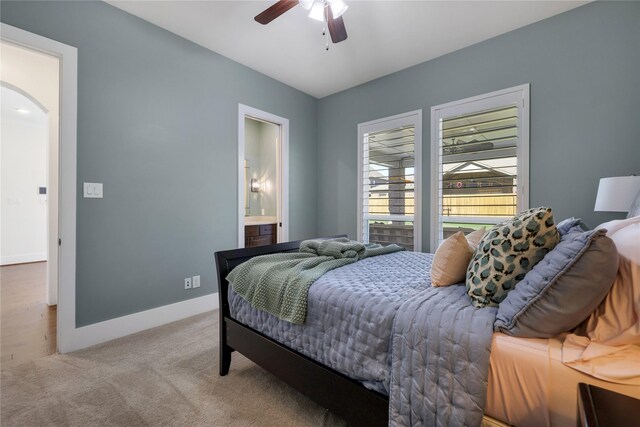 bedroom with light colored carpet, ceiling fan, and ensuite bath