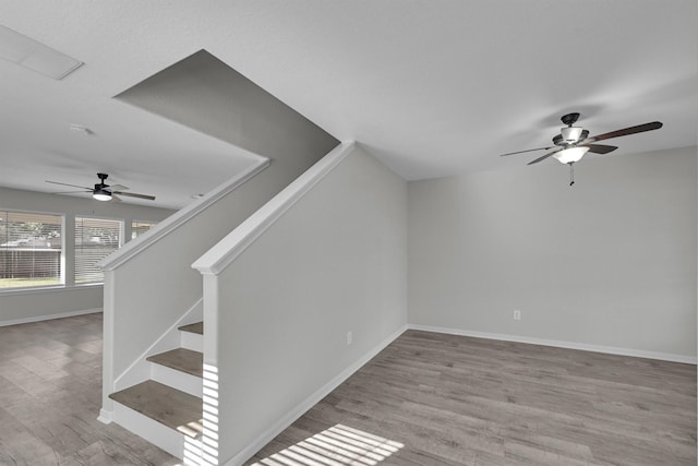 staircase with ceiling fan and hardwood / wood-style floors