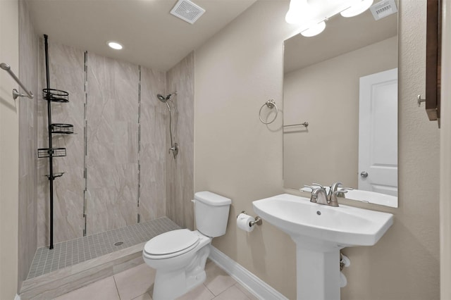 bathroom featuring toilet, tile patterned flooring, and a tile shower