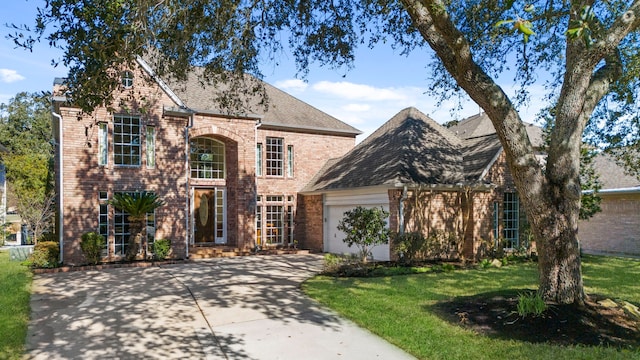 traditional home with an attached garage, a front yard, concrete driveway, and brick siding