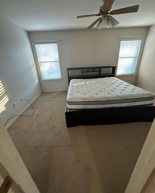 bedroom featuring ceiling fan, light carpet, and multiple windows