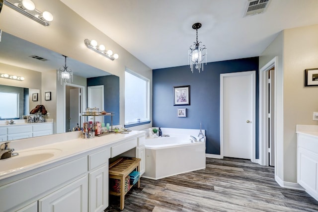 bathroom with a tub to relax in, hardwood / wood-style flooring, plenty of natural light, and vanity