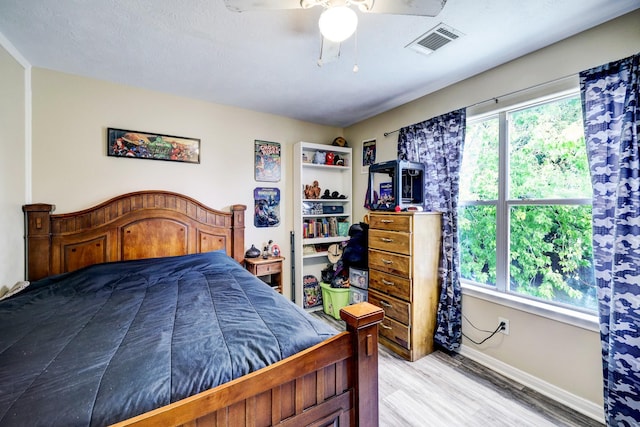 bedroom with light wood-type flooring, ceiling fan, and a textured ceiling