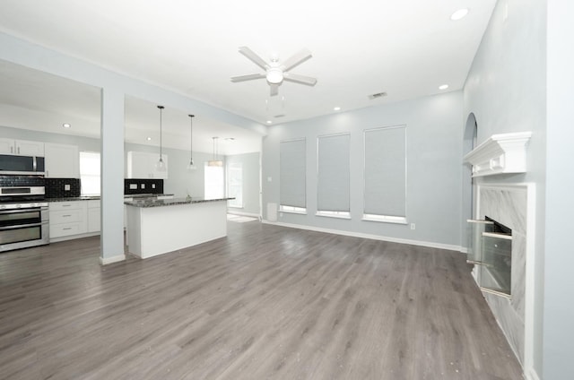 unfurnished living room with ceiling fan, light hardwood / wood-style floors, and a fireplace