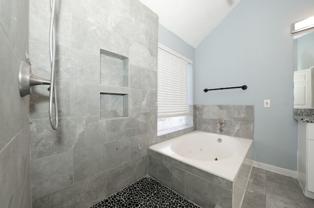 bathroom with vanity, a relaxing tiled tub, and lofted ceiling