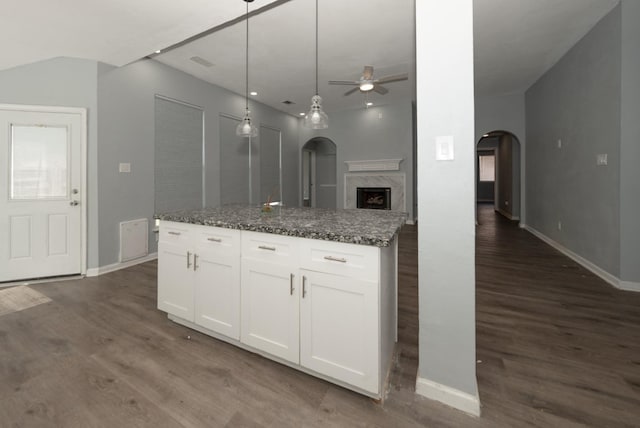 kitchen featuring ceiling fan, dark wood-type flooring, white cabinetry, dark stone countertops, and a kitchen island