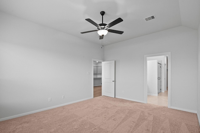 unfurnished bedroom with ceiling fan, light colored carpet, a walk in closet, a closet, and lofted ceiling