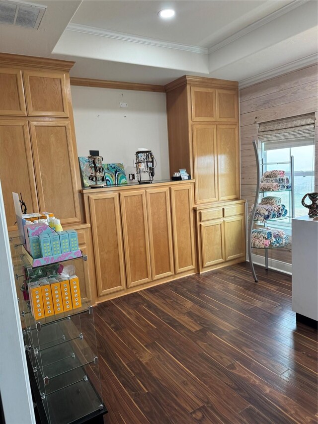 interior space with a raised ceiling, crown molding, and dark hardwood / wood-style flooring