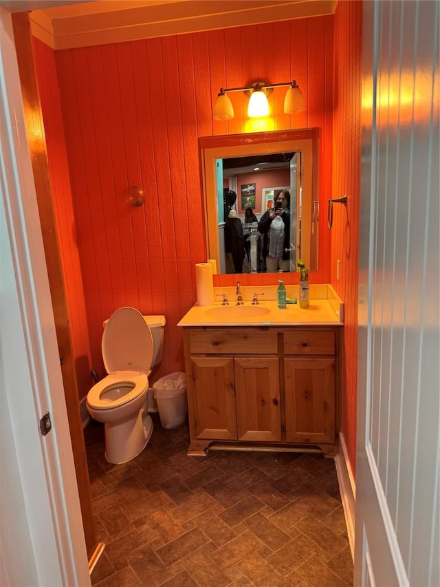 bathroom featuring wooden walls, vanity, and toilet