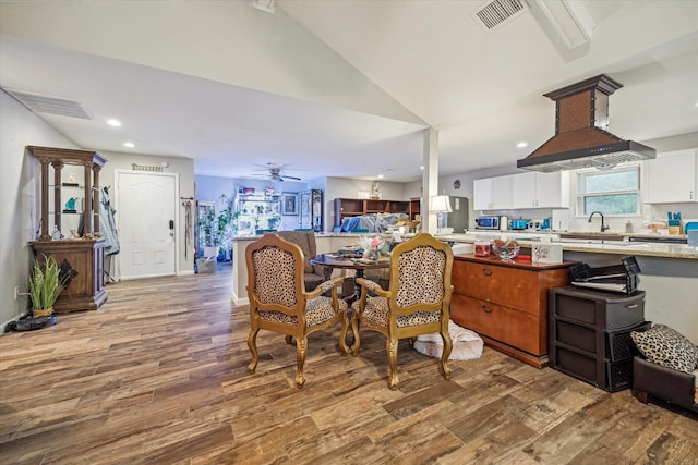 dining space with light wood-type flooring, ceiling fan, sink, and lofted ceiling