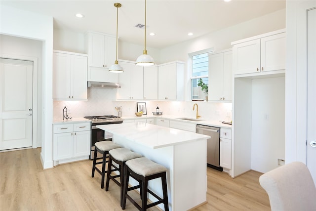 kitchen featuring pendant lighting, white cabinetry, a kitchen island, and appliances with stainless steel finishes