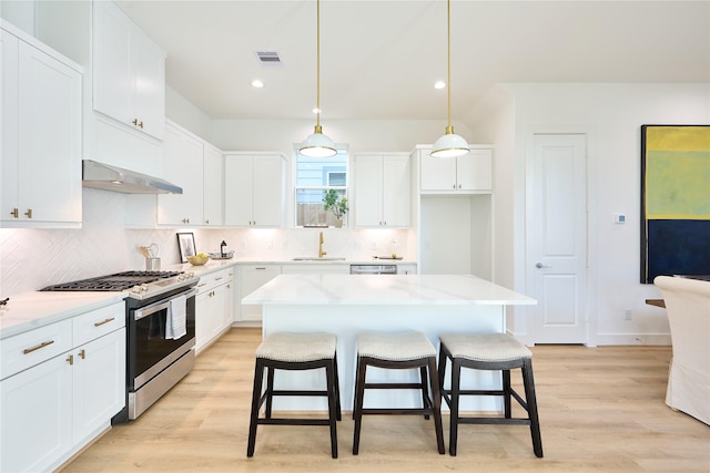 kitchen featuring white cabinetry, gas stove, a center island, and pendant lighting