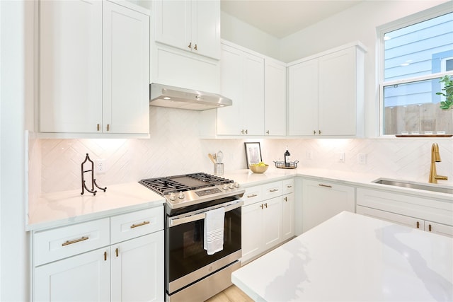 kitchen featuring stainless steel range with gas cooktop, white cabinetry, sink, backsplash, and light stone counters