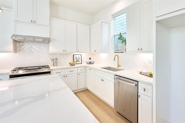 kitchen with sink, stove, white cabinets, stainless steel dishwasher, and light wood-type flooring