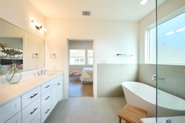 bathroom featuring vanity, tile patterned floors, a tub, and tile walls