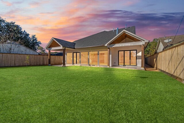 back house at dusk with a yard and a patio area