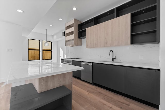 kitchen with appliances with stainless steel finishes, pendant lighting, light brown cabinetry, sink, and light wood-type flooring