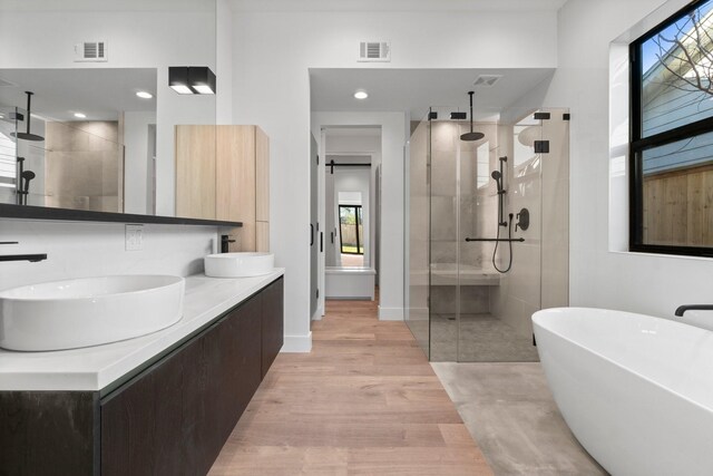 bathroom with vanity, separate shower and tub, a healthy amount of sunlight, and hardwood / wood-style floors