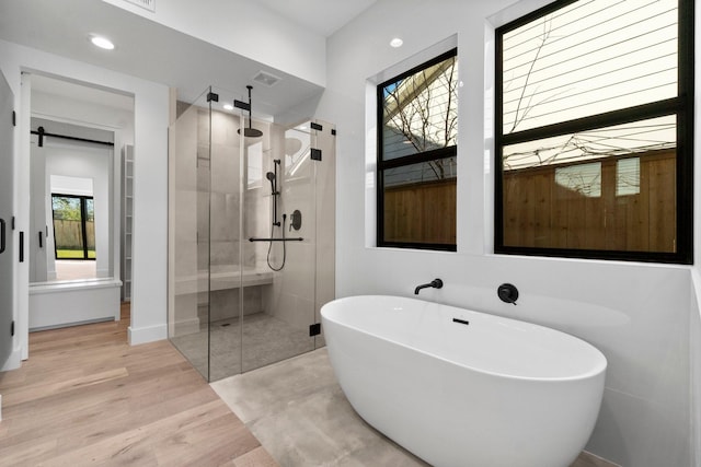 bathroom with hardwood / wood-style flooring and independent shower and bath