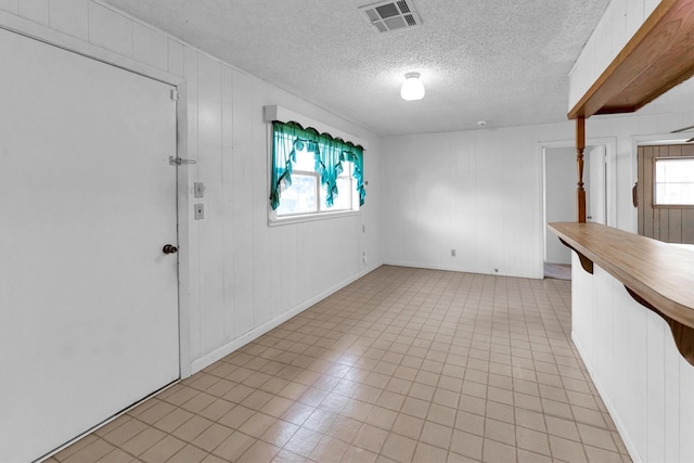 interior space featuring a textured ceiling and wooden walls