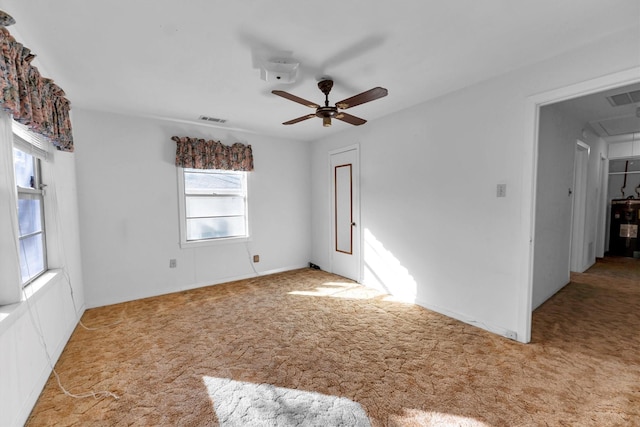 empty room featuring light carpet, water heater, and ceiling fan