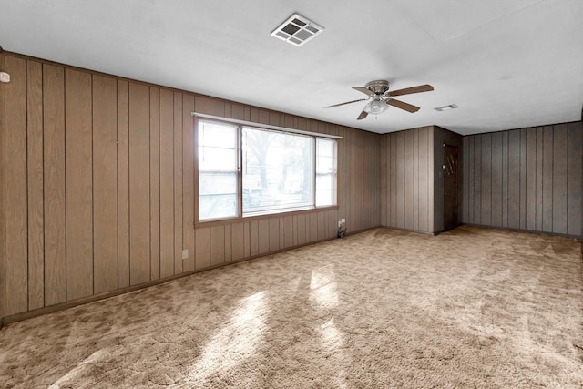 unfurnished room with ceiling fan and wooden walls