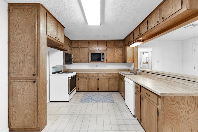 kitchen with sink, white appliances, a textured ceiling, and kitchen peninsula