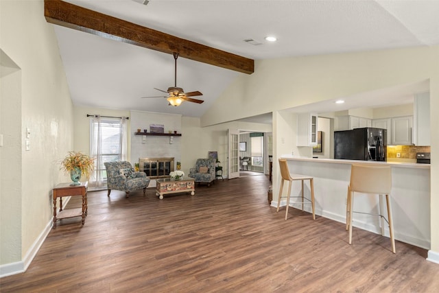 living room featuring a brick fireplace, dark hardwood / wood-style flooring, lofted ceiling with beams, and ceiling fan