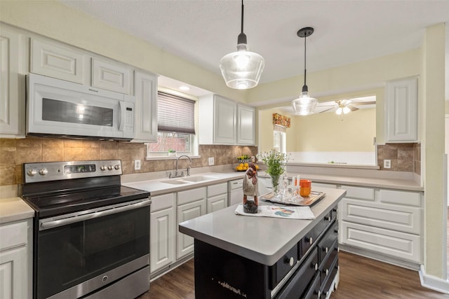 kitchen with a kitchen island, decorative light fixtures, white cabinetry, electric stove, and sink