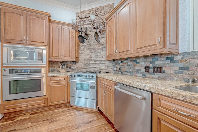 kitchen featuring crown molding, tasteful backsplash, light wood-type flooring, appliances with stainless steel finishes, and light stone countertops