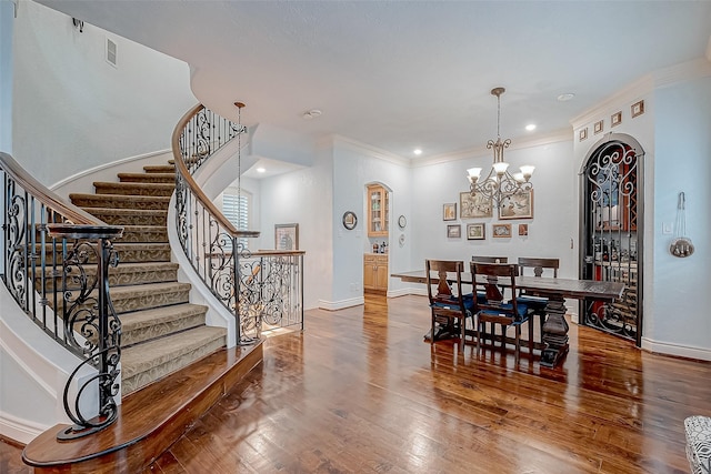 dining area with hardwood / wood-style flooring, crown molding, and a chandelier