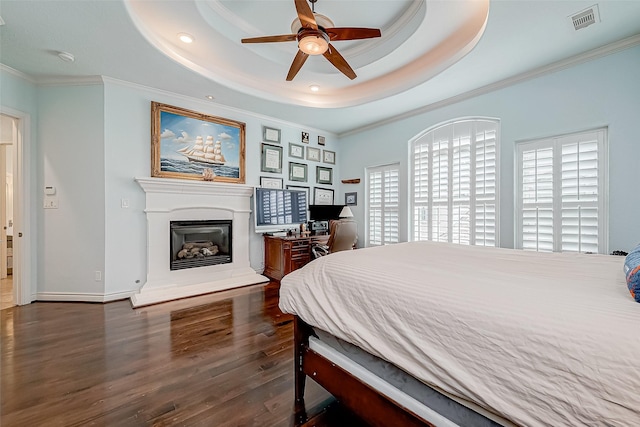 bedroom with ornamental molding, dark hardwood / wood-style floors, and a tray ceiling