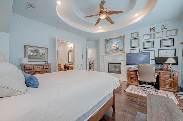 bedroom featuring crown molding, dark hardwood / wood-style floors, ensuite bathroom, and a tray ceiling