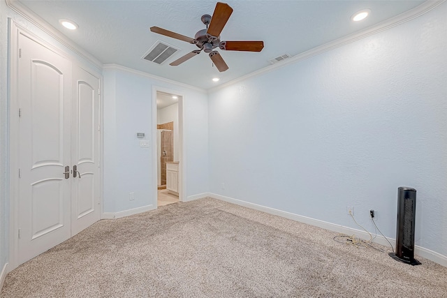 unfurnished bedroom featuring crown molding, ensuite bath, light colored carpet, and ceiling fan