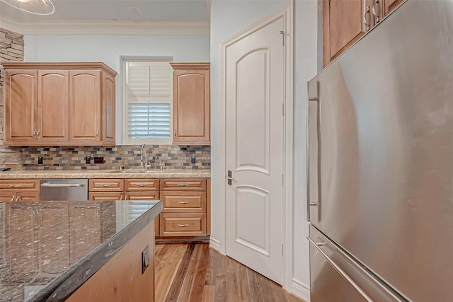 kitchen featuring appliances with stainless steel finishes, sink, backsplash, dark stone counters, and crown molding