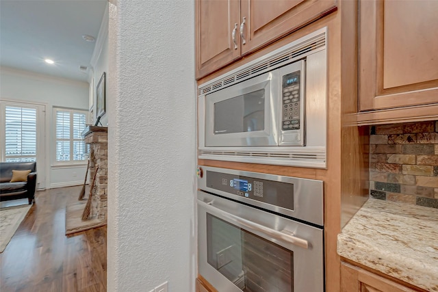 kitchen with light brown cabinetry, crown molding, stainless steel appliances, hardwood / wood-style floors, and decorative backsplash